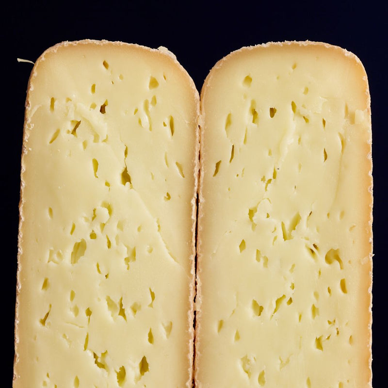 Close up of the nose of a cut pieces of Durrus washed rind cow’s milk cheese, showing the soft, creamy-coloured paste