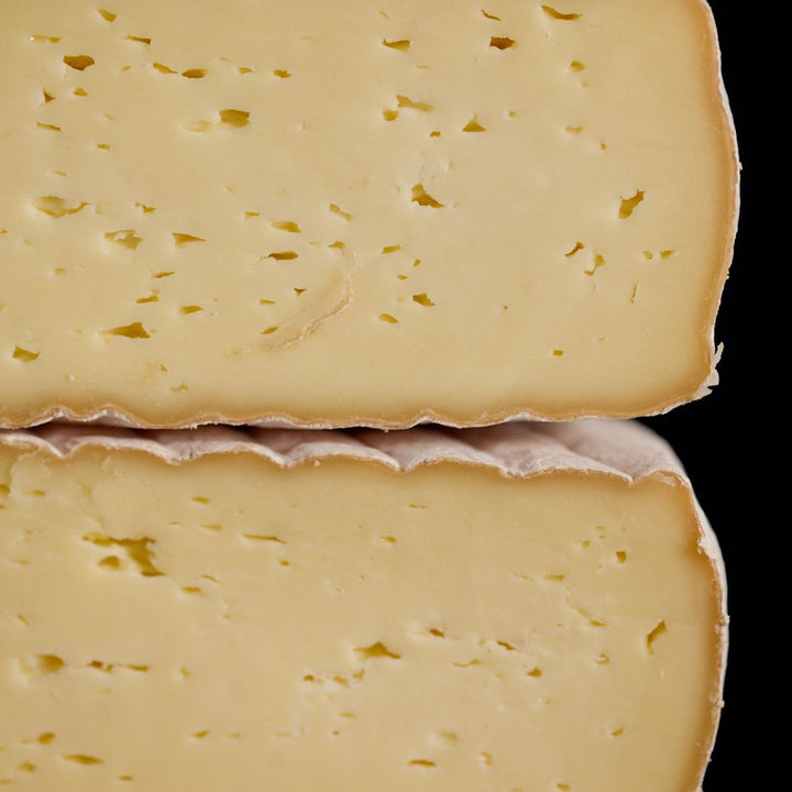 Cross-section of a whole Gubbeen semi-soft washed rind cow’s milk cheese, showing the patterned rind and creamy-coloured paste