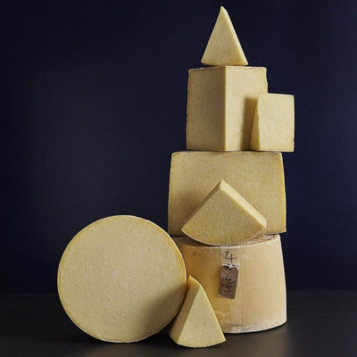 Tower of whole and smaller cut pieces of Kirkham's Lancashire cheeses showing the lard bound outer-casing and crumbly textured paste