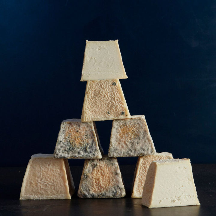 Tower of whole and cut pieces of Sinodun Hill goat’s cheese, with a golden-coloured, mould-flecked, wrinkly rind and light, white paste