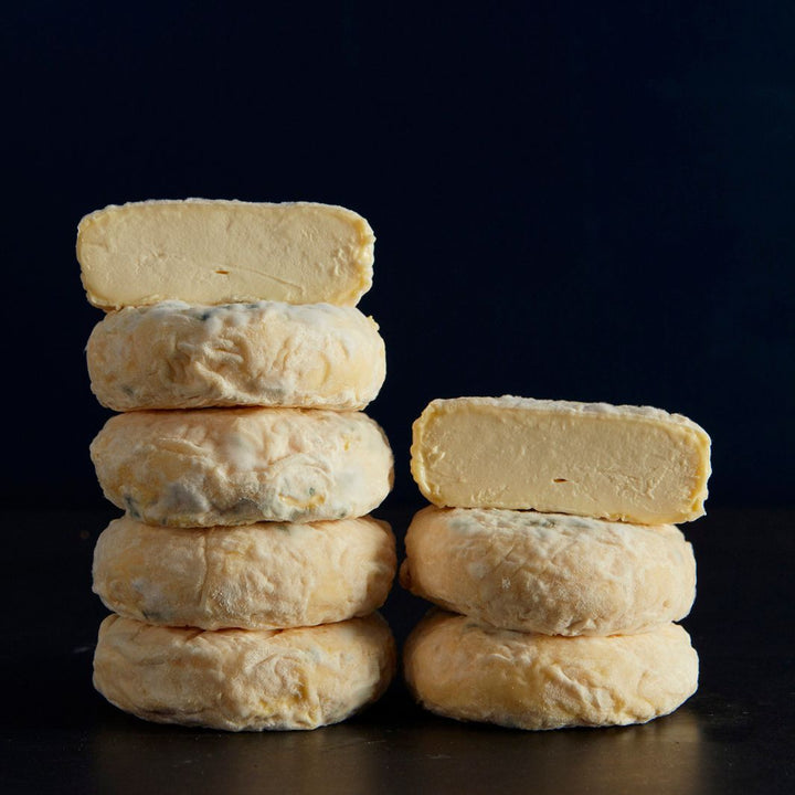Small towers of whole and cut St Jude cow’s milk cheeses with mould-spots on the creamy-coloured wrinkly rind and a light, fluffy, mousse-like paste