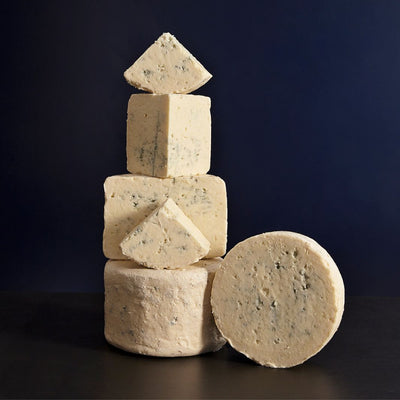 Tower of whole and various sized cut pieces of Beenleigh Blue vegetarian sheep’s cheese with delicate blueing and moist but crumbly texture