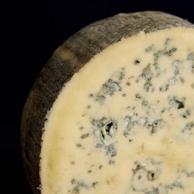 Close up of a cut piece of Cashel Blue vegetarian cow’s milk cheese, showing the blue veining, delicate natural rind and rich, buttery past