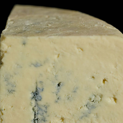 Close up of a cut piece of Devon Blue vegetarian cow’s milk cheese, showing the delicate blue veining and crumbly, buttery texture