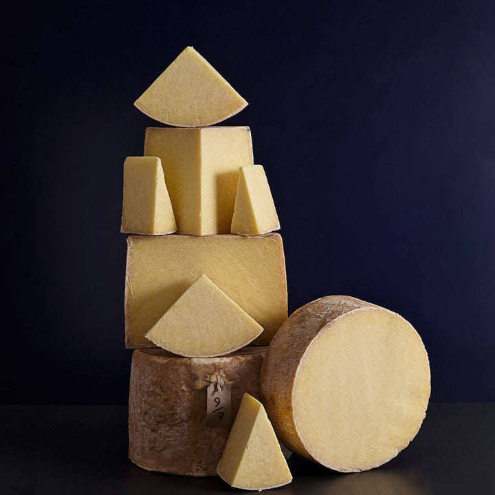 Tower of whole and smaller cut pieces of Mature Kirkham's Lancashire cheeses showing the lard bound outer-casing and crumbly textured paste