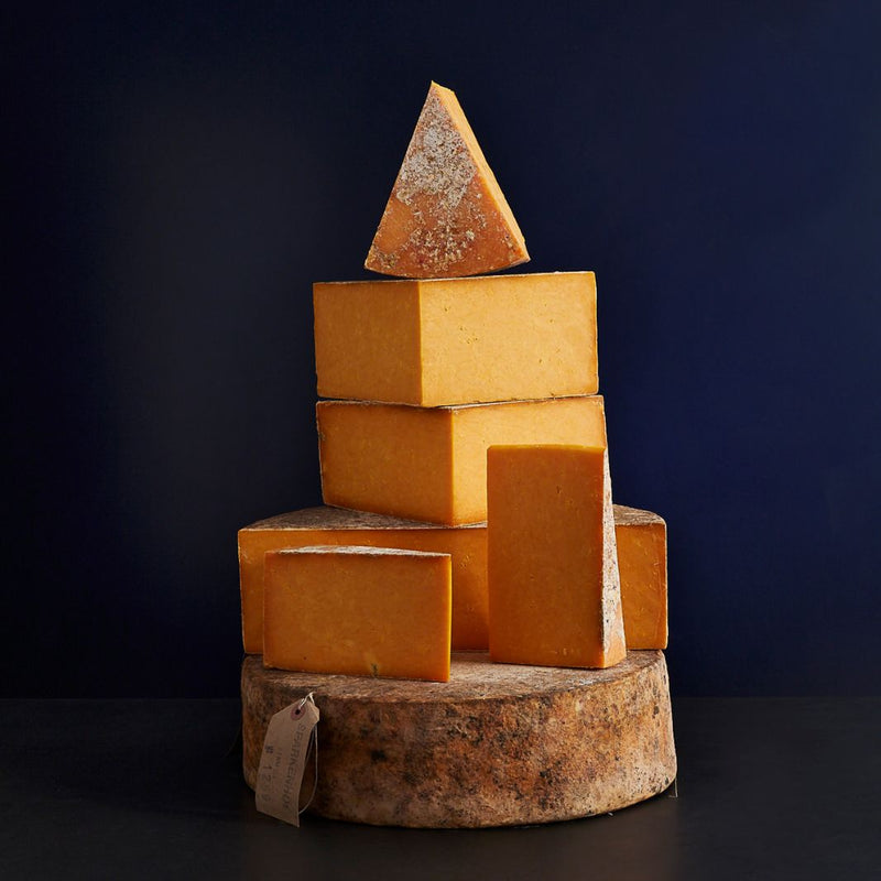 Tower of whole and cut pieces of clothbound Mature Sparkenhoe Red Leicester cheese